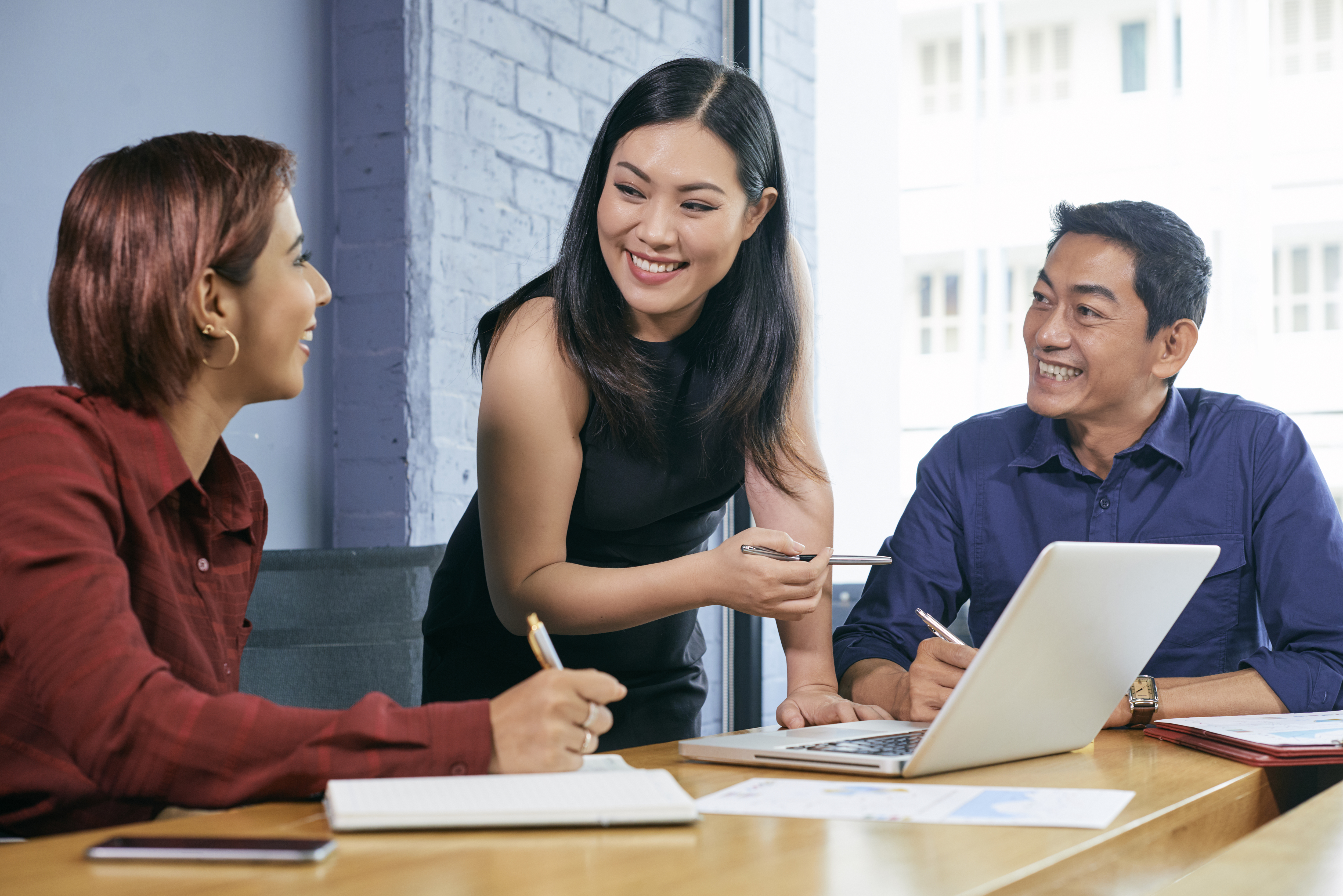 Female entrepreneur conducting meeting Smiling Vietnamese businesswoman discussing presentations on laptop screen with colleagues